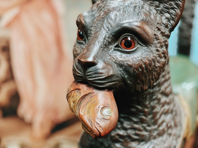 photo of a vintage wooden cat sculpture with fish in its mouth