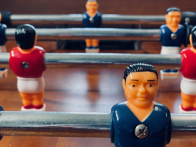 closeup of foosball figures on rods with blue and red jerseys